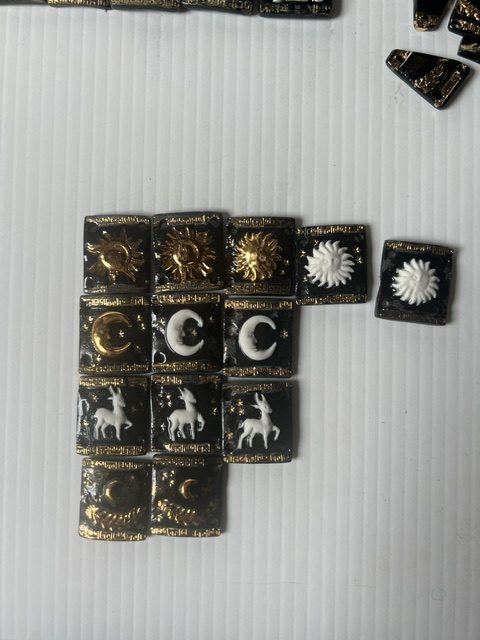 Plaques de porcelaine noire rehaussées d'or : soleils, croissants de lune, biches et laurier